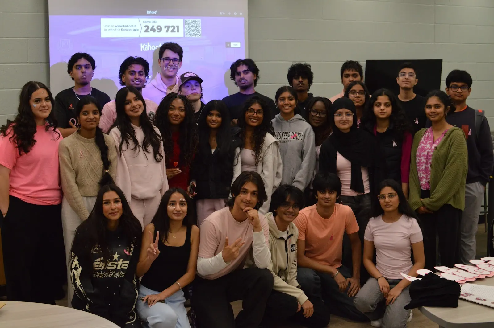Around forty students, many in pink, posing together at the end of FHI's breast cancer awareness event