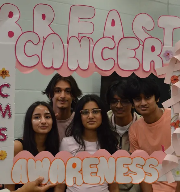Students holding a hand-made Breast Cancer Awareness photo frame