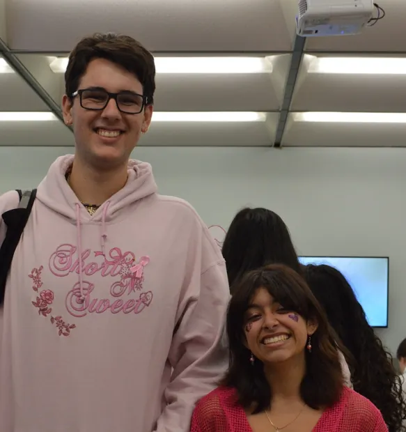 A smiling student in a pink hoodie at FHI's breast cancer awareness event